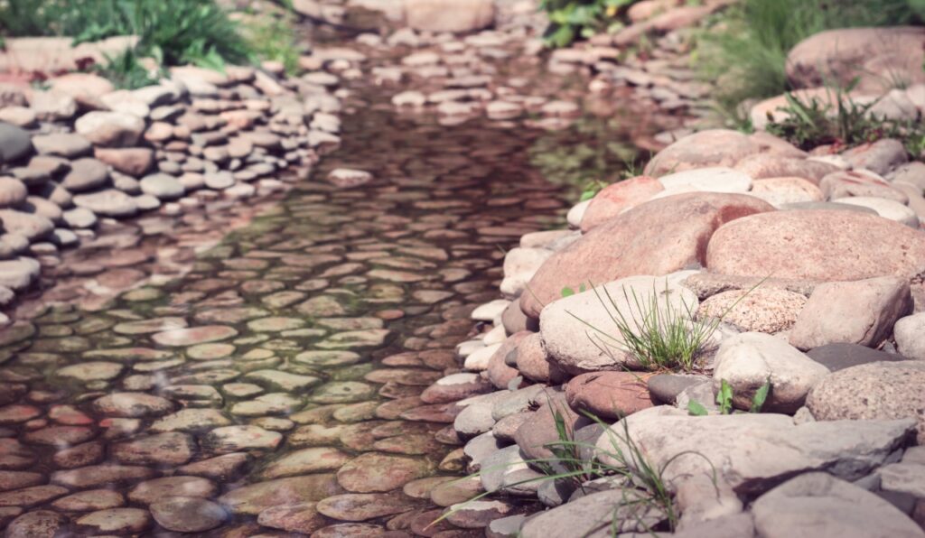 river rock vs mulch | River rock installed in a residential drainage swale
