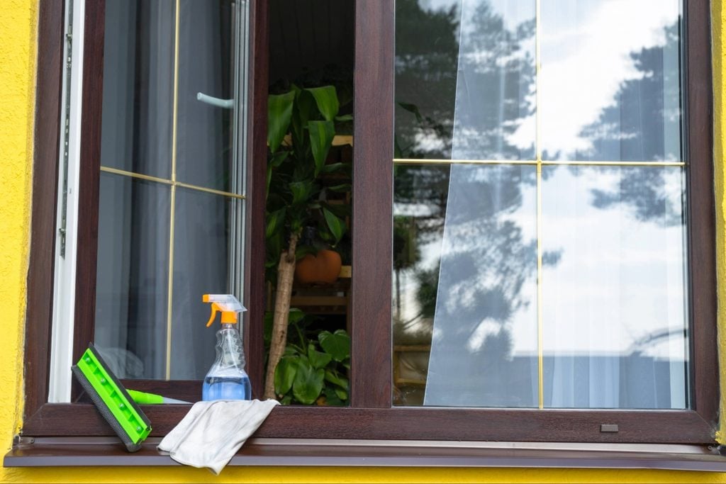 Residential window frame and small exterior gaps being inspected for possible ant entry points