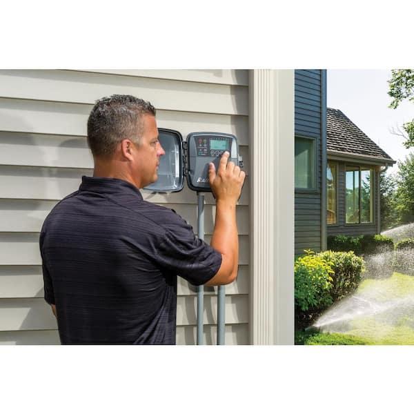 Homeowner checking irrigation controller settings before adjusting the dry season watering schedule