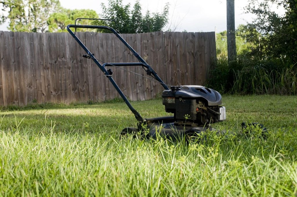 Lawn mower parked beside a residential lawn while grass conditions are checked after heavy rainfall