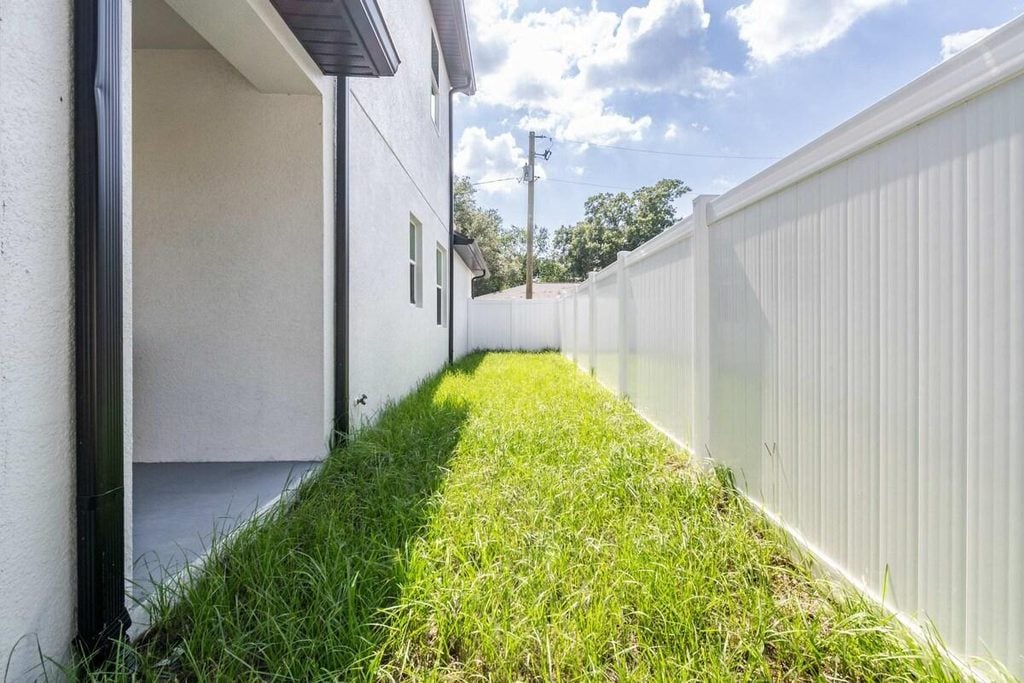 Residential side yard with damp grass and narrow access that should be checked before mowing